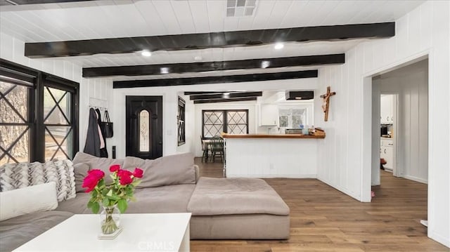 living area featuring visible vents, beam ceiling, baseboards, and wood finished floors