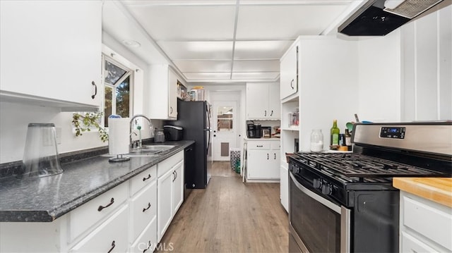 kitchen featuring white cabinetry, light wood-style flooring, exhaust hood, and stainless steel gas range