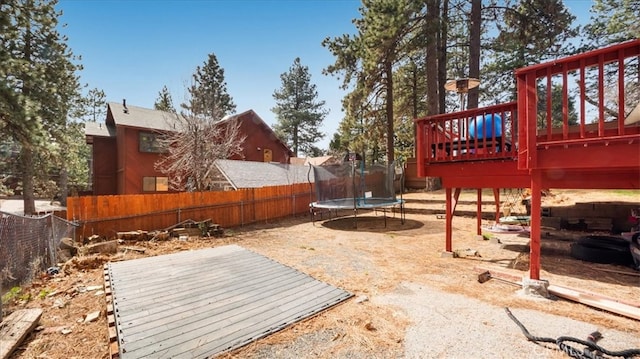 view of yard with a wooden deck, a trampoline, and a fenced backyard