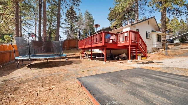 rear view of house with stairway, a trampoline, a deck, and fence