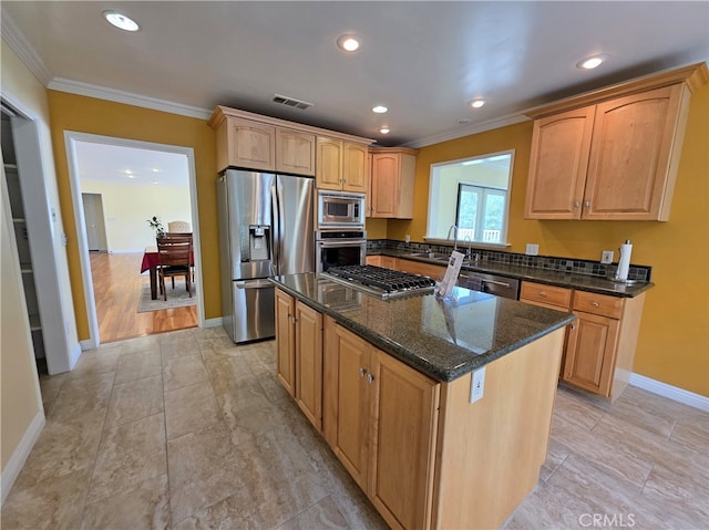 kitchen with visible vents, a kitchen island, crown molding, appliances with stainless steel finishes, and a sink