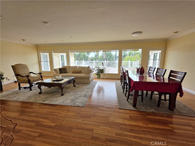 living area with baseboards, wood finished floors, and ornamental molding