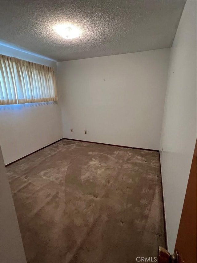 unfurnished room with a textured ceiling and carpet floors