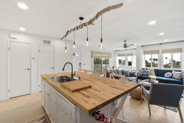 kitchen featuring recessed lighting, visible vents, white dishwasher, a sink, and wood counters