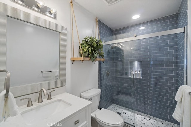 full bath featuring toilet, visible vents, tiled shower, and vanity