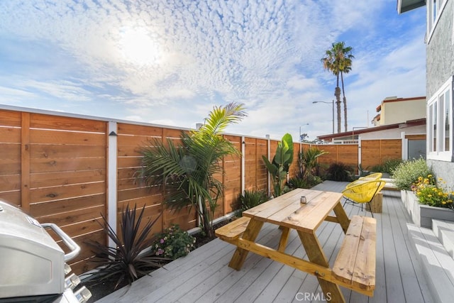 wooden terrace featuring outdoor dining space and a fenced backyard