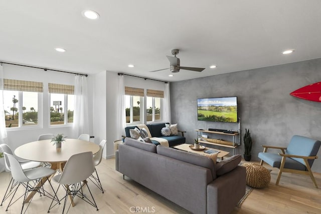 living room featuring light wood-type flooring, ceiling fan, an accent wall, and recessed lighting