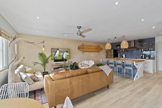 living room featuring light wood-style flooring, ceiling fan, and recessed lighting