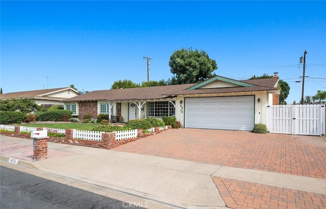 single story home featuring an attached garage, a gate, fence, and decorative driveway