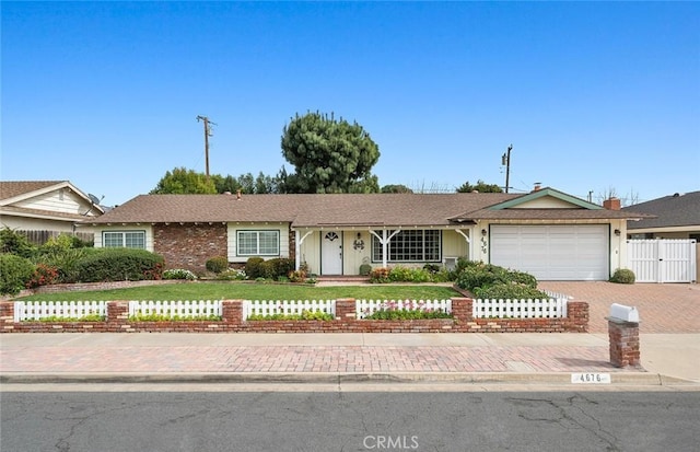 ranch-style house with an attached garage, fence, and decorative driveway