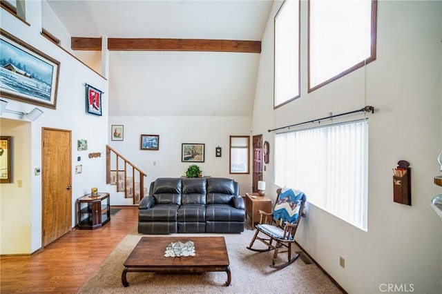 living area with beam ceiling, a high ceiling, and stairs