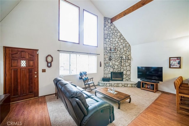 living area featuring beam ceiling, high vaulted ceiling, wood finished floors, and a fireplace