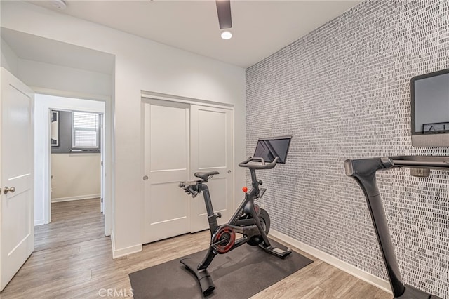 workout room with recessed lighting, baseboards, light wood-style floors, and an accent wall