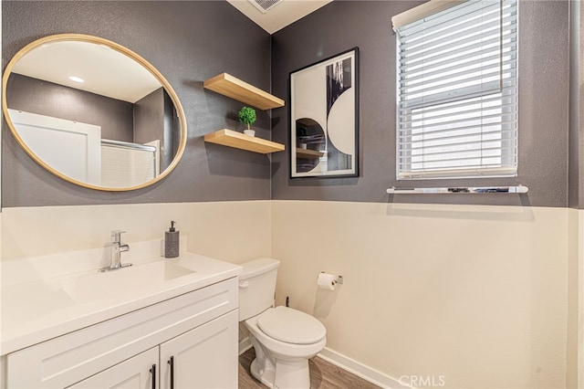 bathroom with vanity, wood finished floors, visible vents, baseboards, and toilet