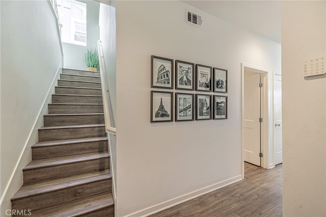 staircase with visible vents, baseboards, and wood finished floors