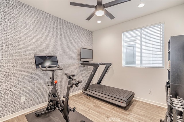 exercise area featuring an accent wall, baseboards, recessed lighting, wood finished floors, and a ceiling fan