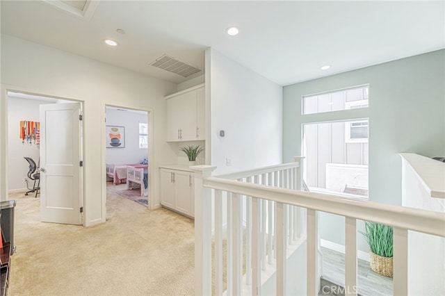 hall with recessed lighting, visible vents, light carpet, and an upstairs landing