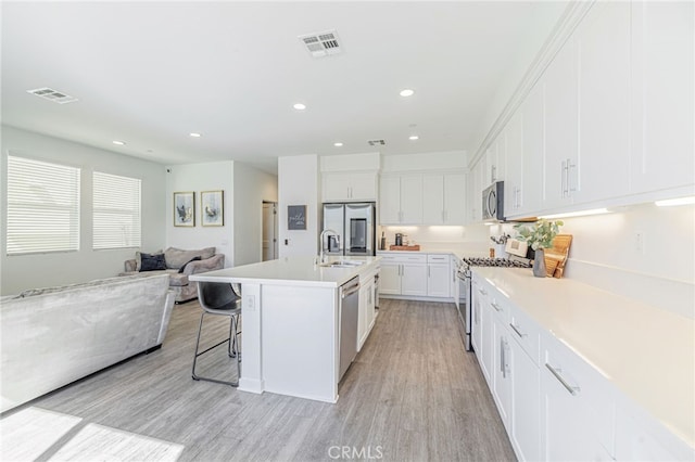 kitchen with visible vents, light wood-style flooring, a sink, appliances with stainless steel finishes, and open floor plan