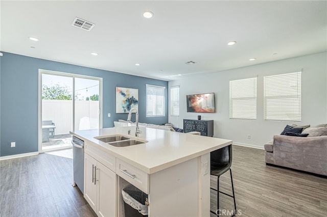 kitchen with wood finished floors, visible vents, a sink, dishwasher, and open floor plan