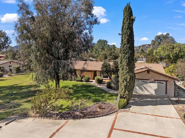 view of front facade featuring stucco siding, a tiled roof, driveway, and fence