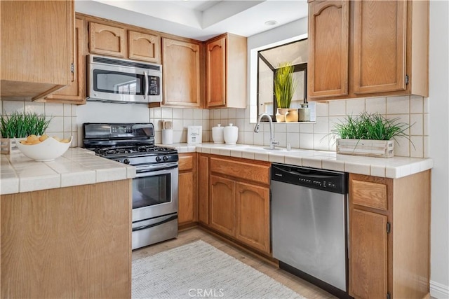 kitchen with appliances with stainless steel finishes, a sink, and tasteful backsplash