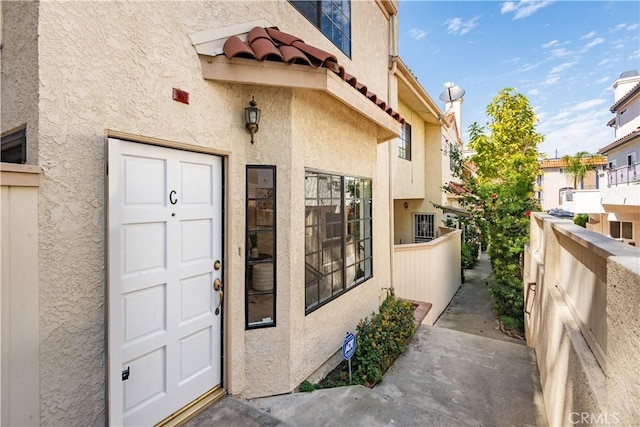 doorway to property featuring a tile roof and stucco siding