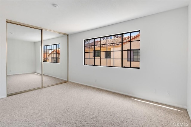 unfurnished bedroom with a closet, carpet, and baseboards