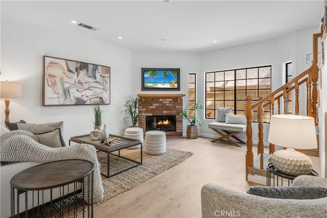 living area featuring recessed lighting, a brick fireplace, visible vents, and wood finished floors