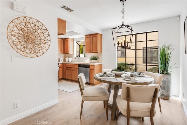 dining area with visible vents, light wood-style flooring, baseboards, and an inviting chandelier