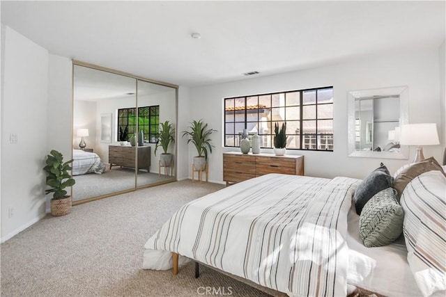 carpeted bedroom with visible vents and a closet