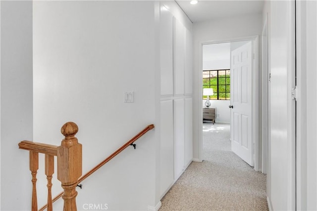 corridor featuring an upstairs landing and light colored carpet