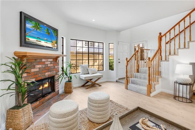 living area with baseboards, a fireplace, stairway, and wood finished floors