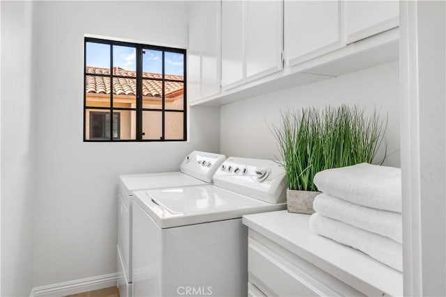 clothes washing area with cabinet space, baseboards, and washer and clothes dryer