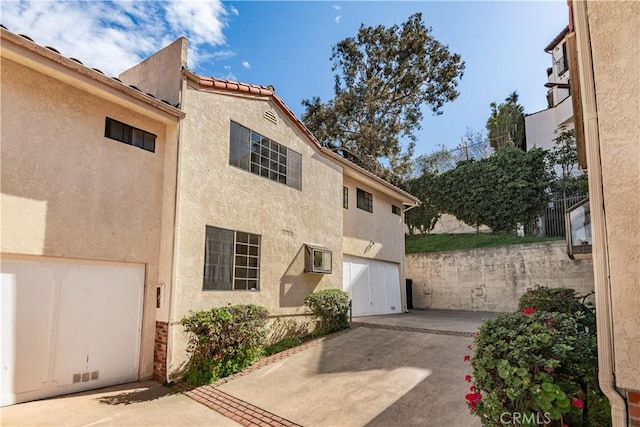 exterior space featuring concrete driveway, a patio area, and stucco siding