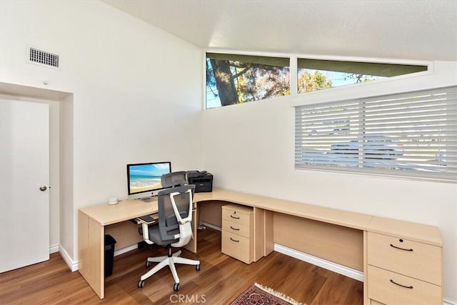 office area featuring visible vents, built in study area, baseboards, and wood finished floors