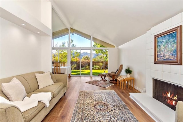 living room with lofted ceiling with beams, wood finished floors, and a fireplace