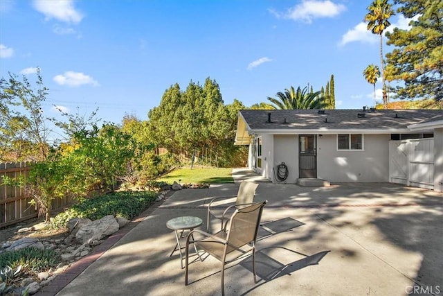 rear view of house featuring stucco siding, a patio, and fence