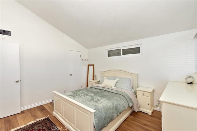 bedroom with lofted ceiling, light wood-style flooring, baseboards, and visible vents