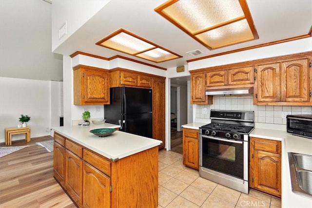 kitchen with visible vents, black appliances, light countertops, under cabinet range hood, and backsplash