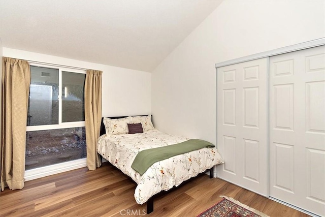 bedroom featuring a closet, vaulted ceiling, and wood finished floors