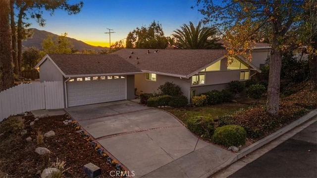 view of front of home with stucco siding, an attached garage, concrete driveway, and fence