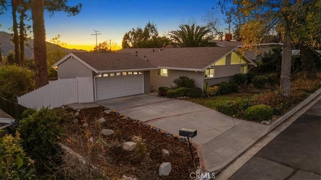 view of front facade with a garage, concrete driveway, stucco siding, and fence