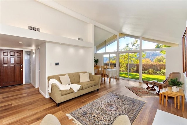 living area with beam ceiling, visible vents, high vaulted ceiling, and wood finished floors