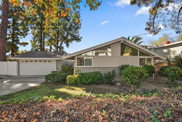 mid-century modern home featuring fence, a garage, and driveway