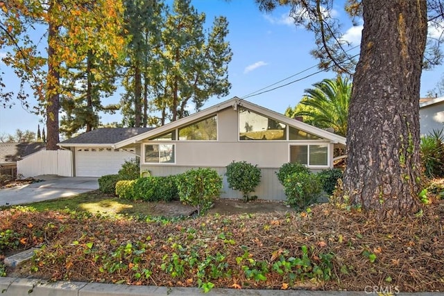 mid-century home with concrete driveway, fence, and a garage