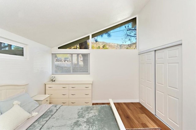 unfurnished bedroom with a closet, wood finished floors, and vaulted ceiling