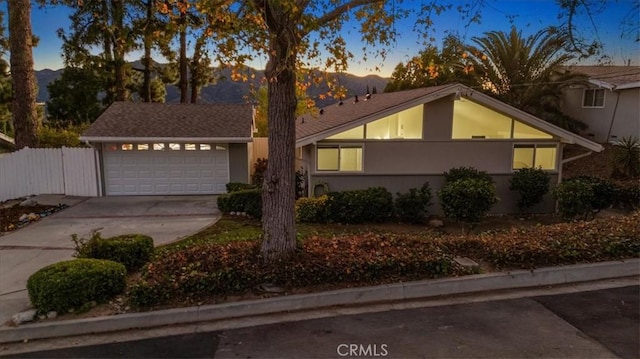 view of front of home featuring stucco siding, an attached garage, concrete driveway, and fence