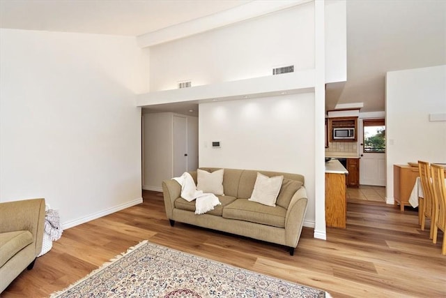 living room featuring light wood finished floors, visible vents, and baseboards