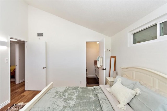 bedroom with visible vents, wood finished floors, and vaulted ceiling