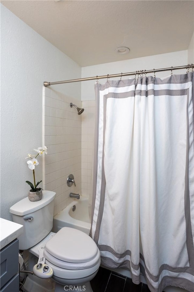 full bath featuring a textured wall, tile patterned flooring, toilet, vanity, and shower / bath combo